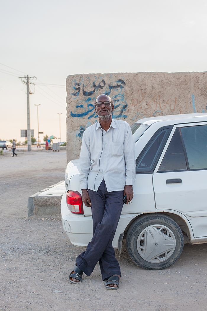 Mahdi EhsaeiA man leaning against one of the most sold cars in Iran, a Kia Pride. The nearly extinct cult car is the Peykan.