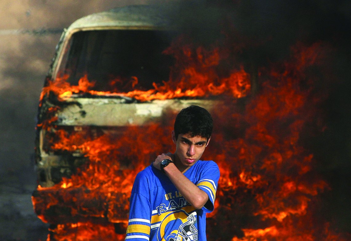 GAZA CITY, -: A Palestinian youth stands in front of a burning vehicle during clashes between rival Fatah and Hamas in Gaza City, 14 May 2007. Two Palestinians were killed in fresh fighting between rival Fatah and Hamas gunmen today despite a truce aimed at ending the worst factional violence since a unity government took office. AFP PHOTO/MOHAMMED ABED (Photo credit should read MOHAMMED ABED/AFP/Getty Images)