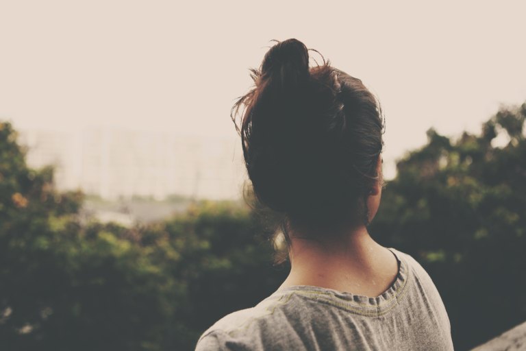 Back of brunette woman's head overlooking trees