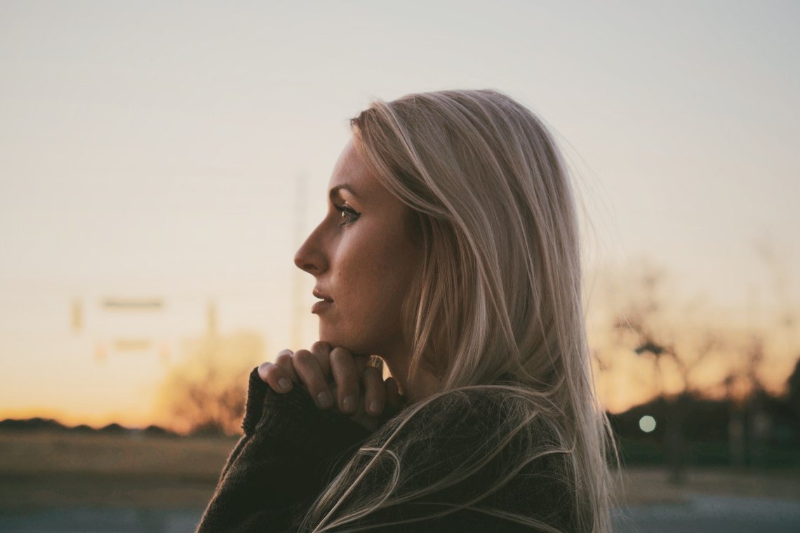 Blonde woman at sunset praying