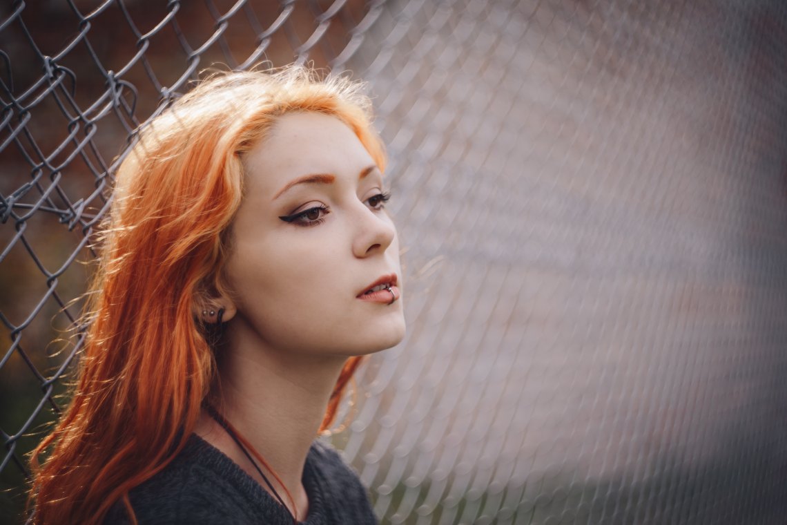 redhead leaning on fence