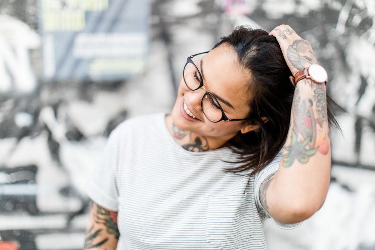 tattooed woman standing in front of wall