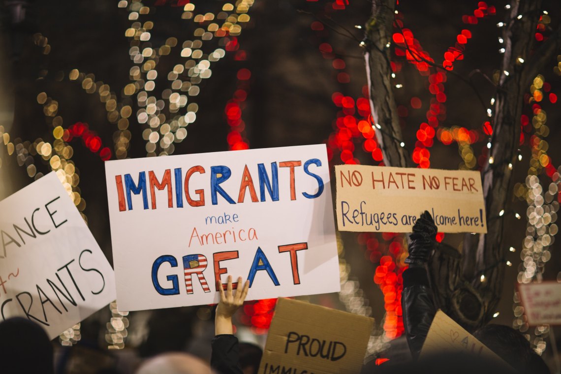 People hold up pro-immigration signs at a protest