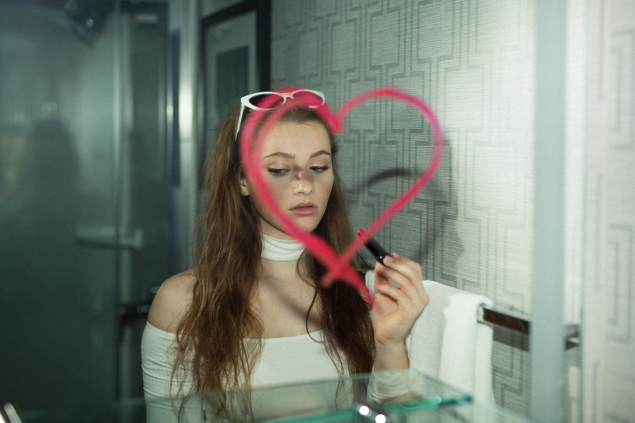 pink lipstick on mirror with girl's reflection