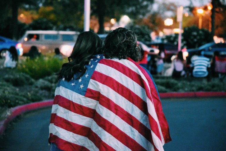 Two women stand with an American flag draped over their shoulders in solidarity