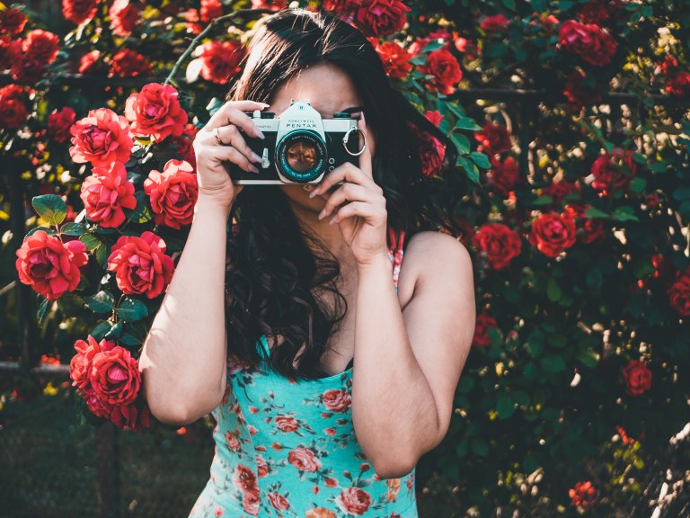 girl in flowers with camera, happy girl, endless possibilities