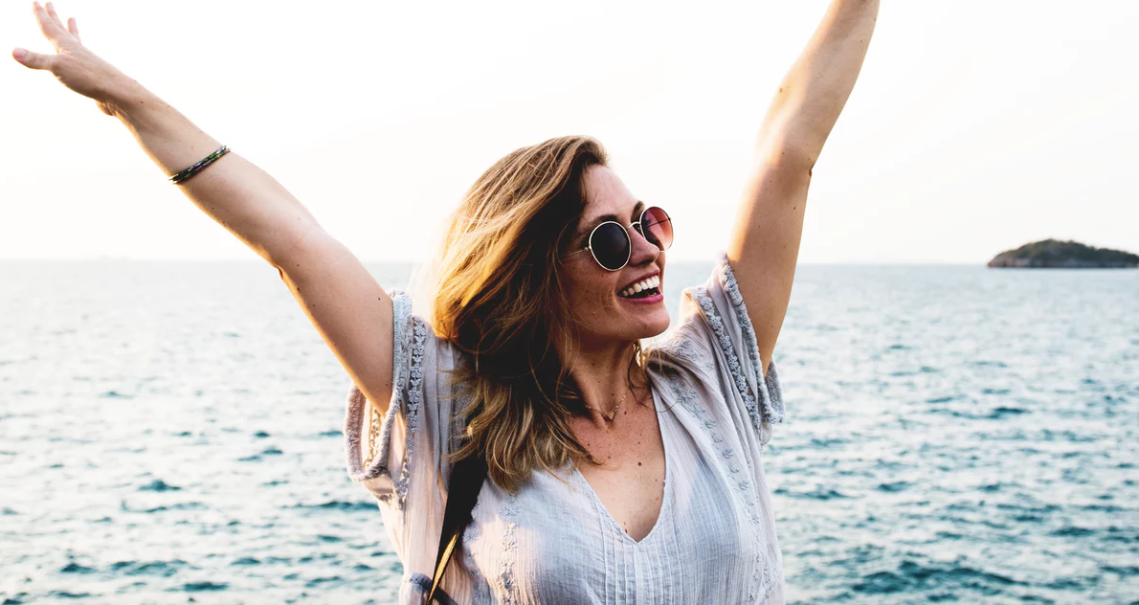 Woman laughing in front of ocean