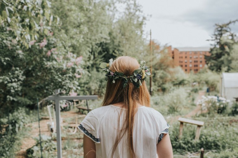 Woman stands with her back to the camera with a flower crown in her hair