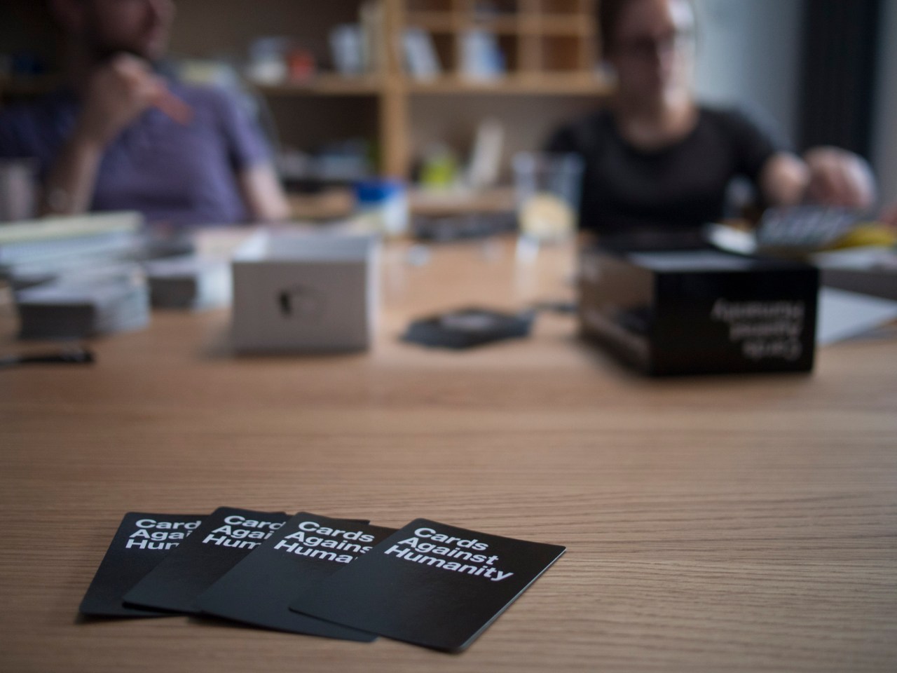 Friends sitting around a table playing Cards Agaisnt Humanity