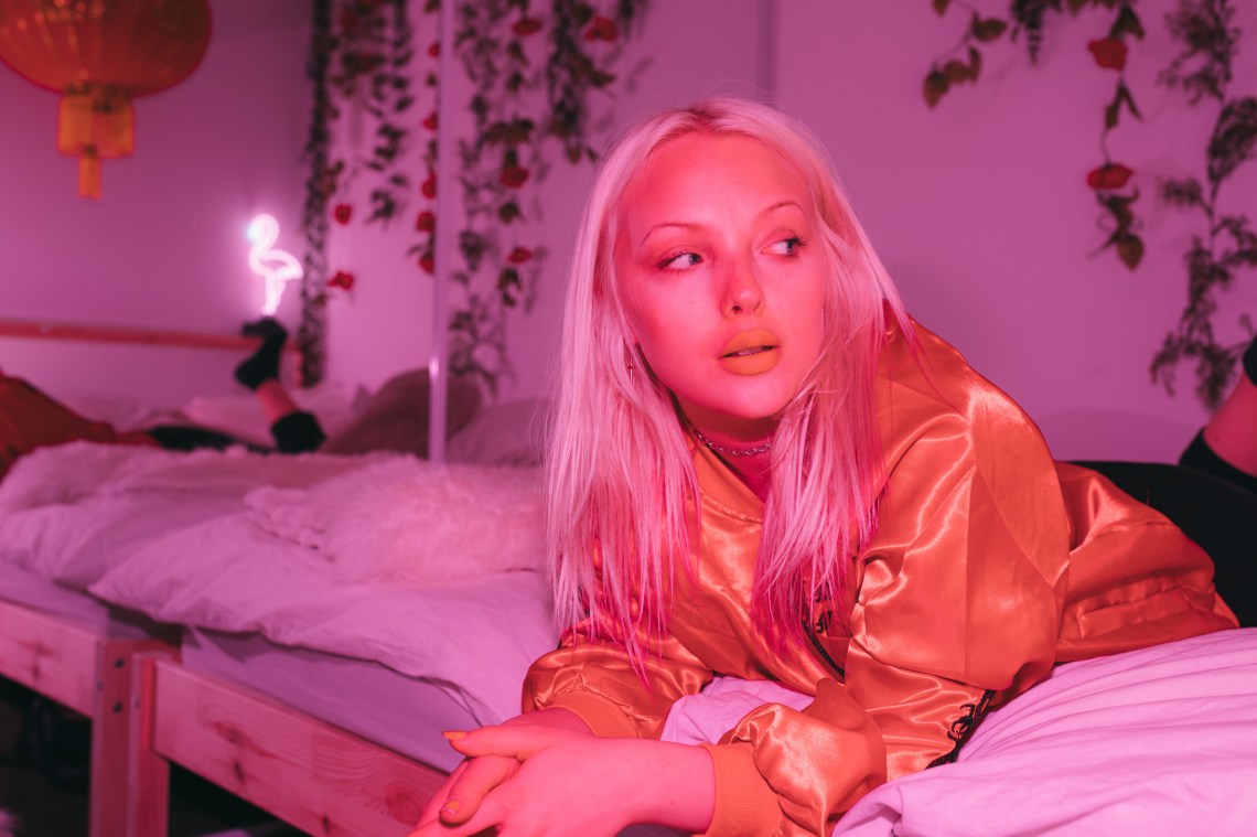 girl lying on a bed pink lighting