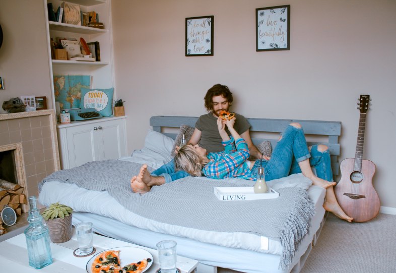 couple eating pizza in bed together