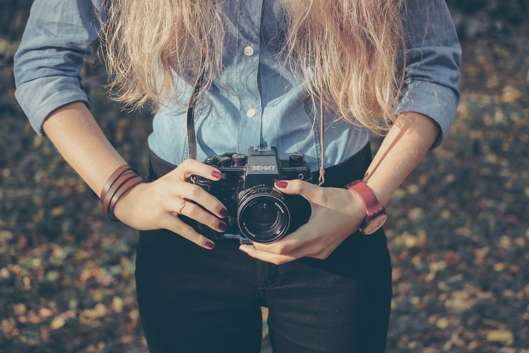 A close-up of a woman holding a Behnt Zenit camera.