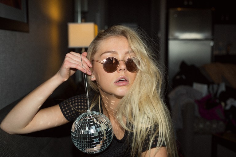 woman in sunglasses holding disco ball