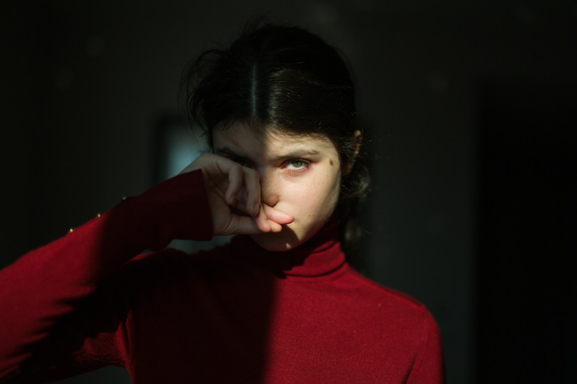 girl in a red turtleneck half lit