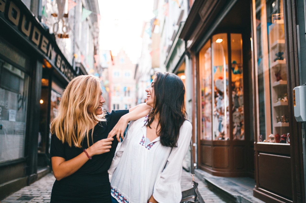 two friends laughing while walking down the street