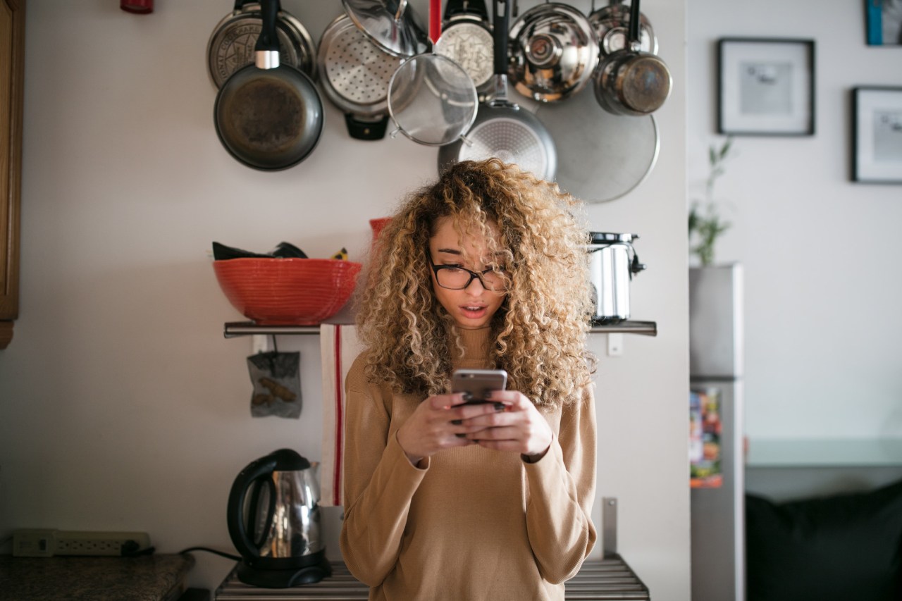 Fascinated girl in kitchen reading an article on a website