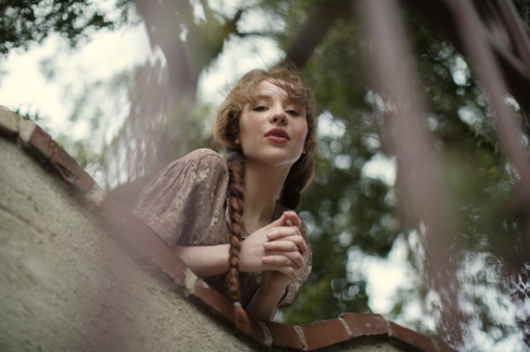 Lovely girl in braids looks down from the castle wall like Juliet Capulet