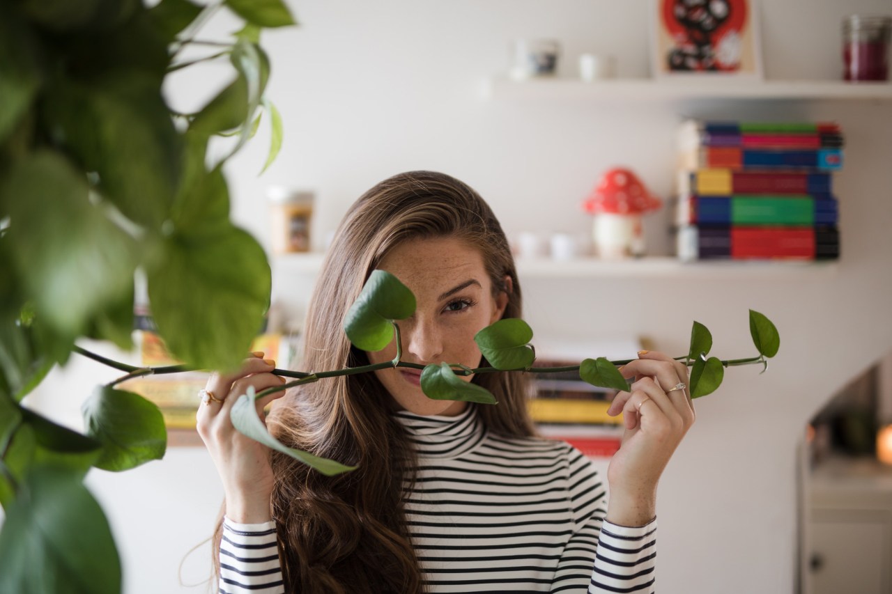 girl hiding behind stem of leaves