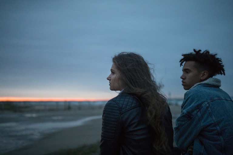 Silent Couple Contemplate as They Sit Together by the Beach