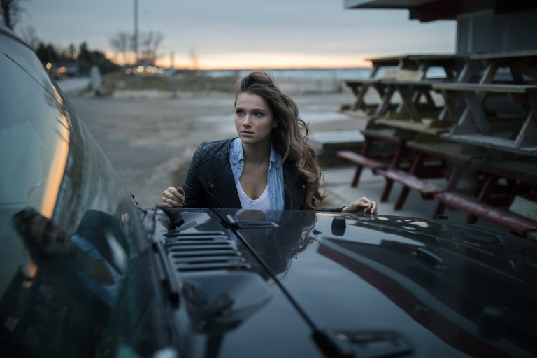 woman standing behind car