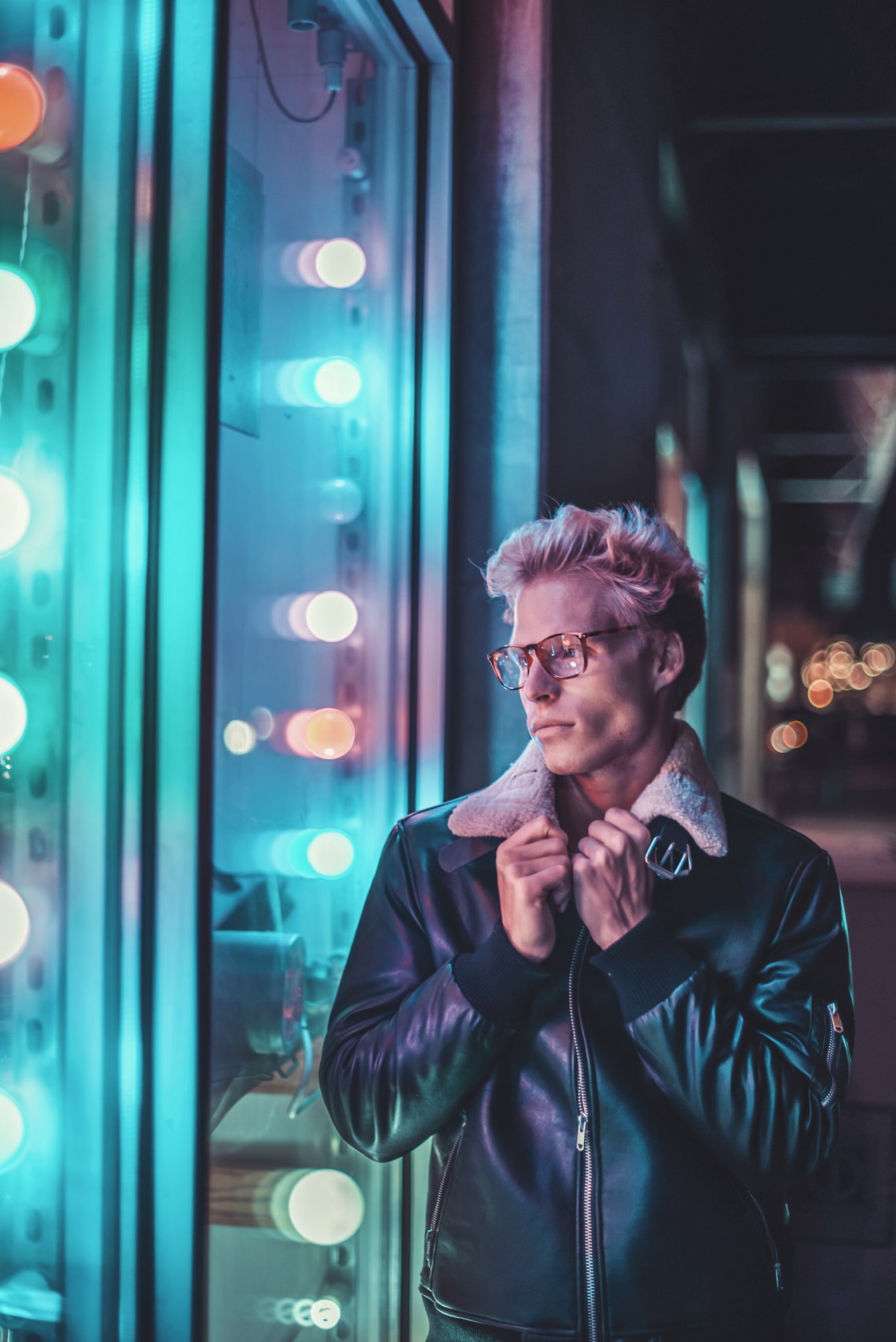 young man look into a window blue and pink lighting