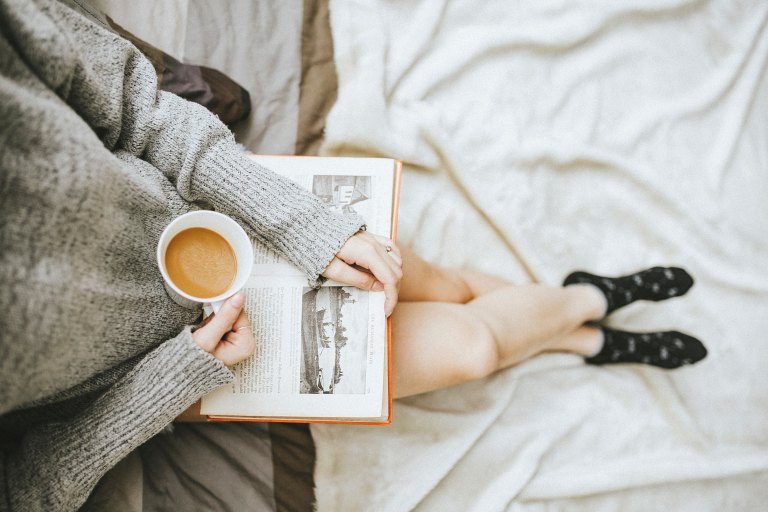 woman reading with coffee in bed