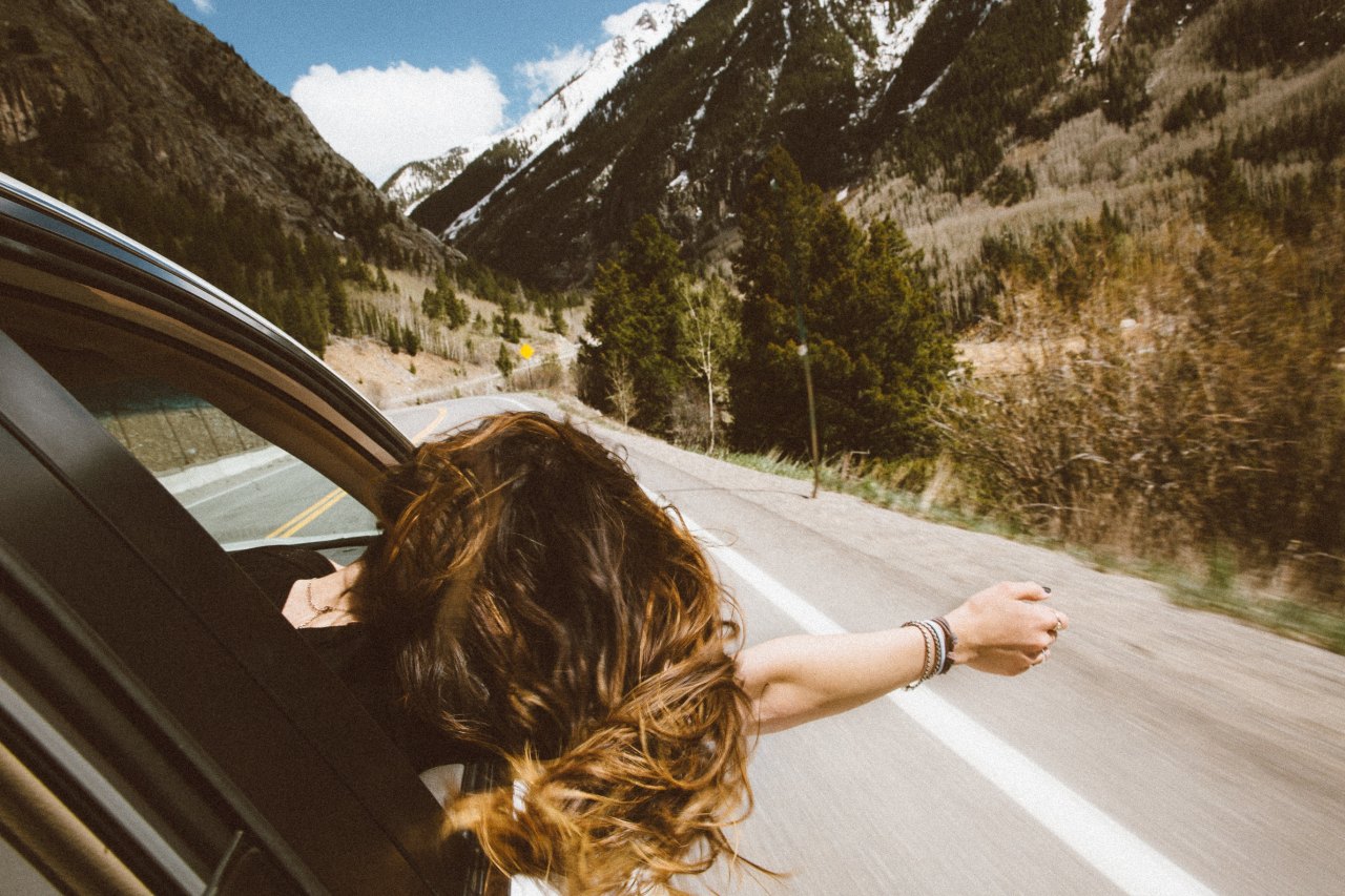 carefree woman stick hand out car window