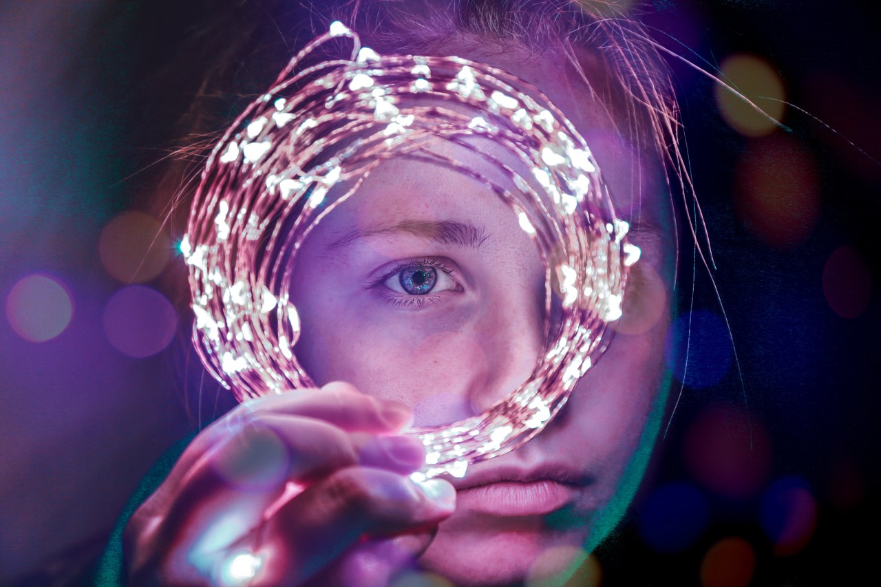 girl holding up a string of lights