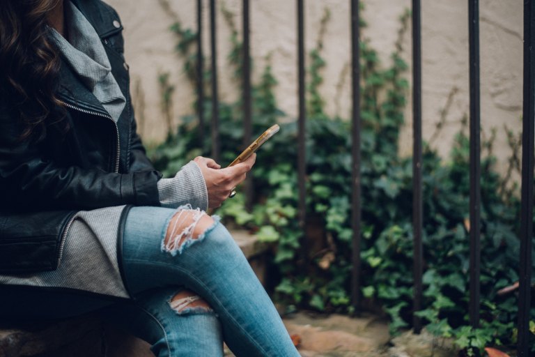 girl in ripped jeans texting