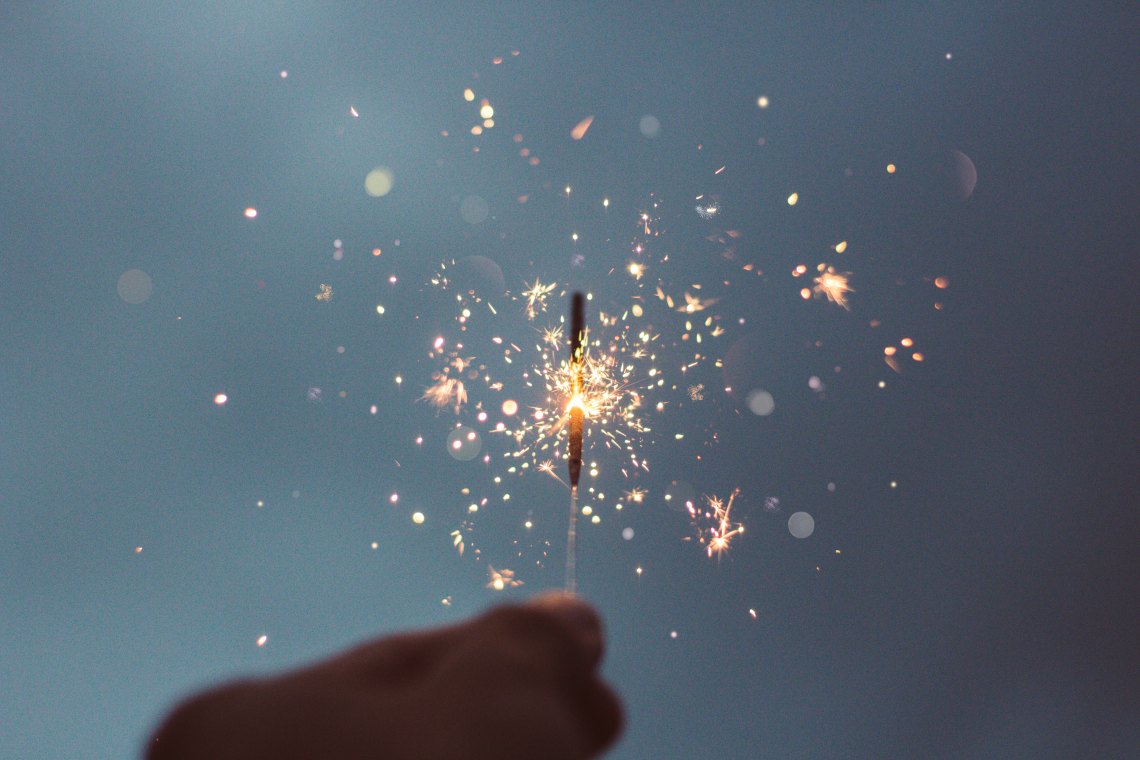 hands holding sparkler at dusk