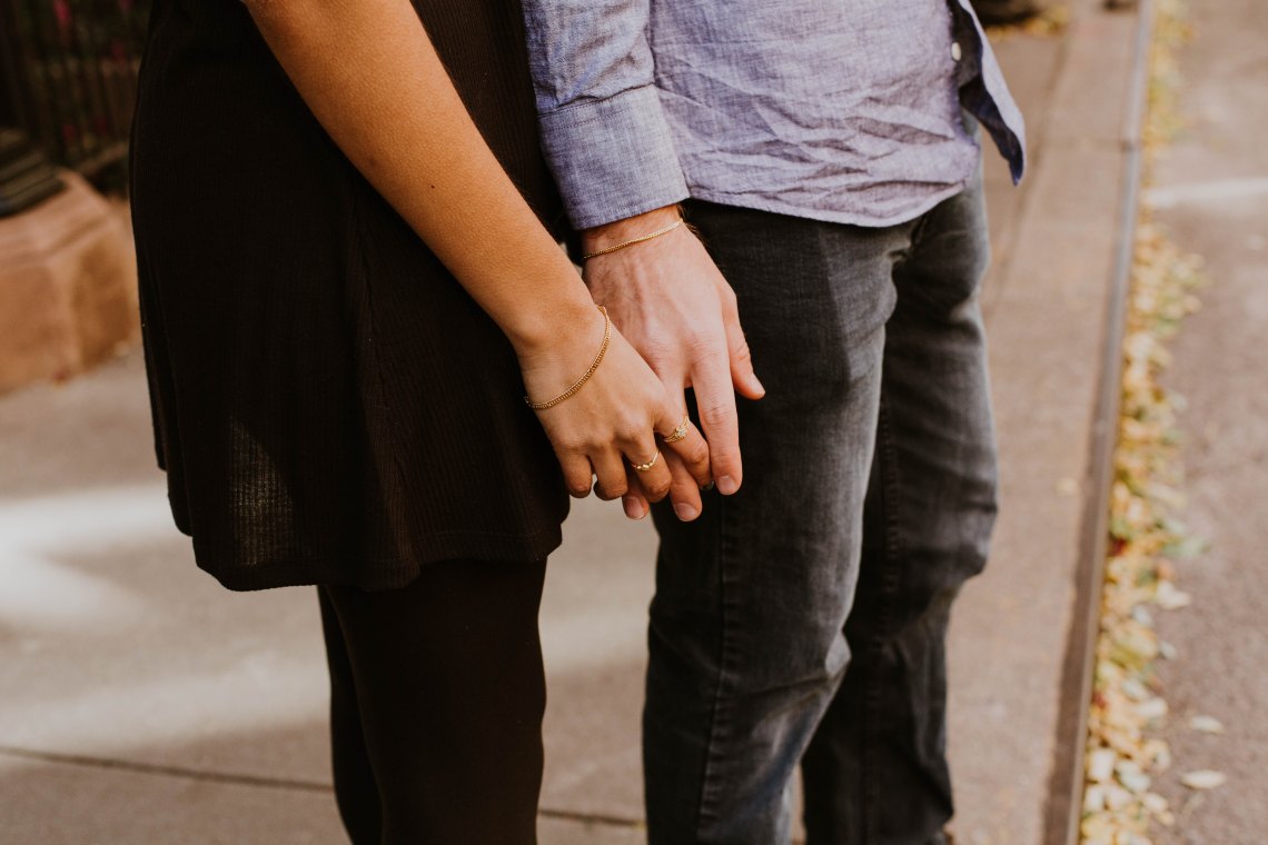 Woman holds onto a man's hand from behind