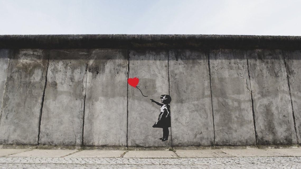 graffiti of a woman holding a heart balloon on the Berlin wall