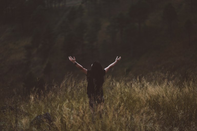 person in a field arms extended