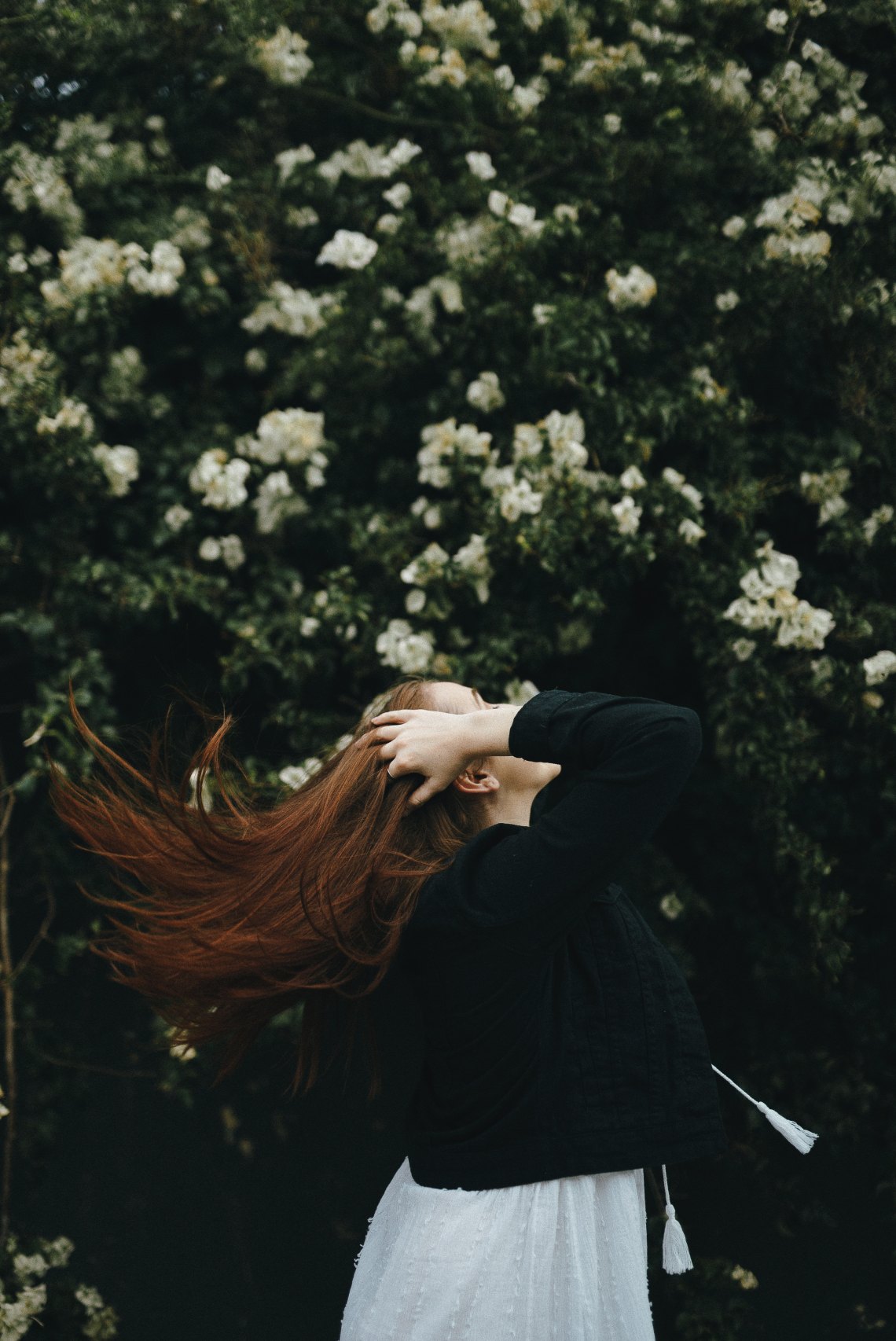 woman flipping hair by some flowers