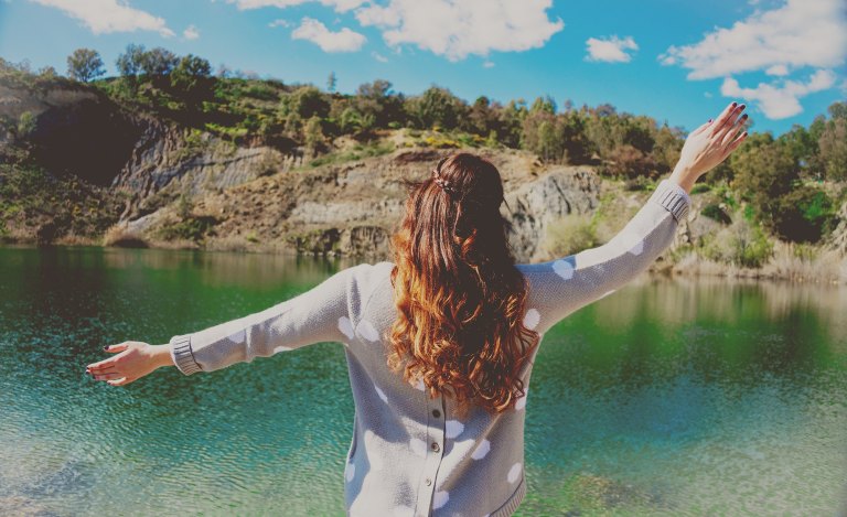 woman standing in front of lake carefree