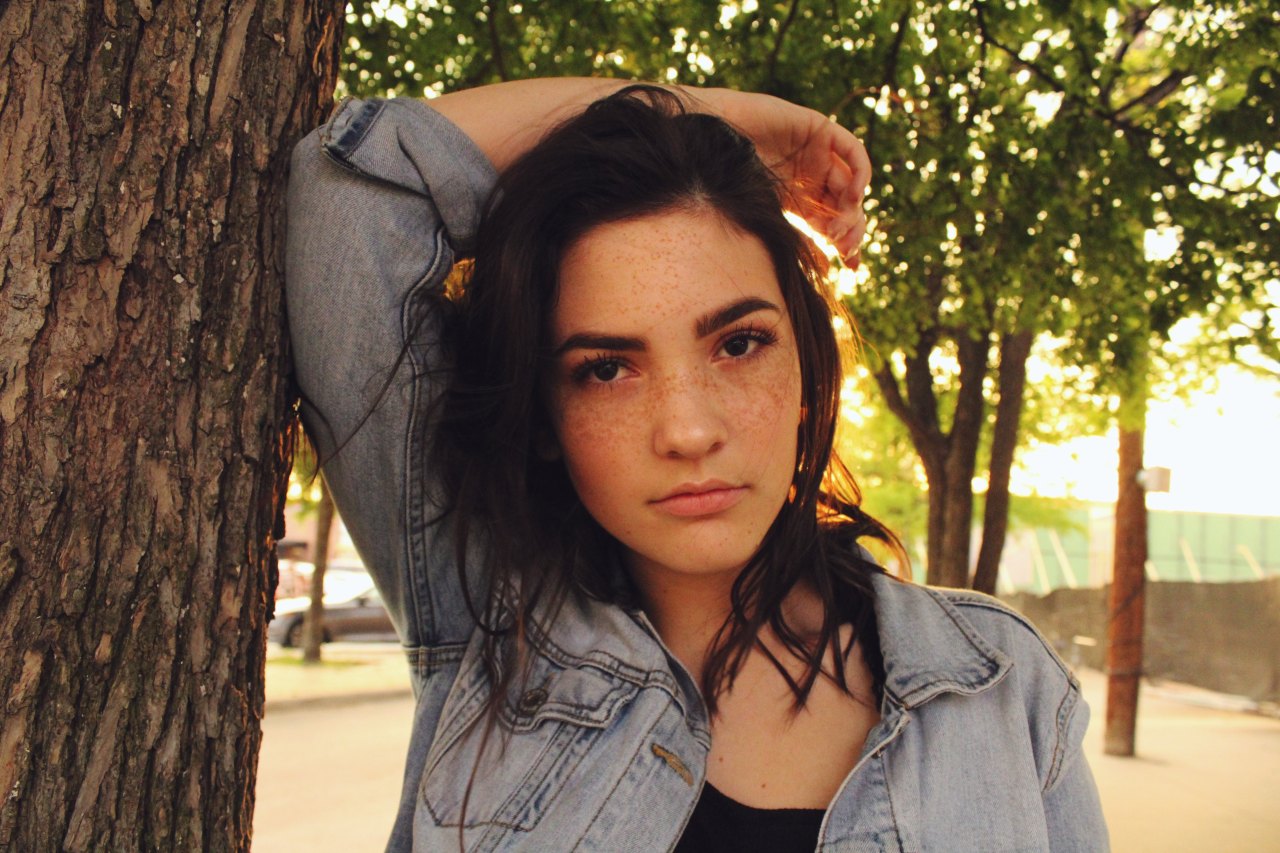 girl leaning on a tree with her arm above her head