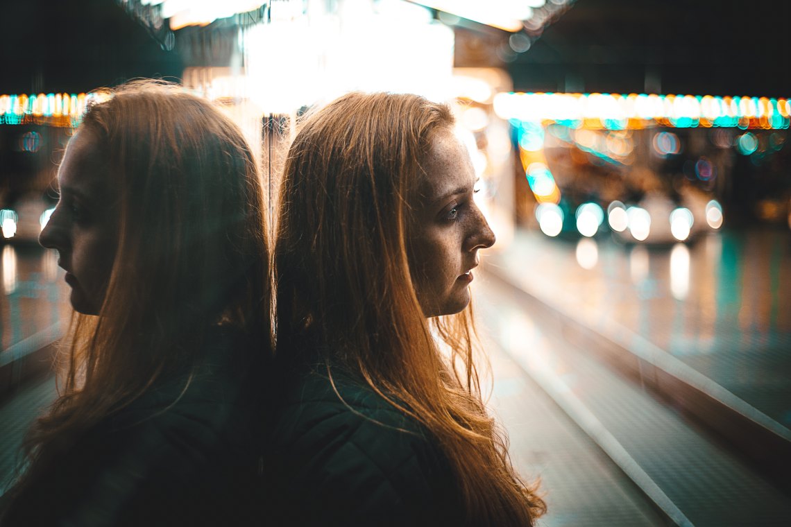 girl leaning against a mirror next to a street