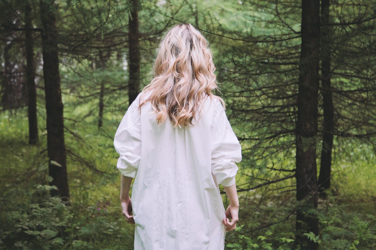 blonde girl walking away in a forest