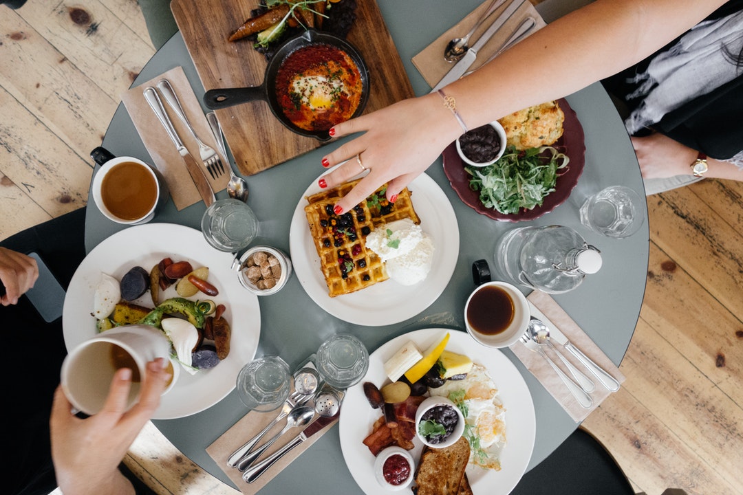 People eating huevos rancheros, waffles, and breakfast food for brunch