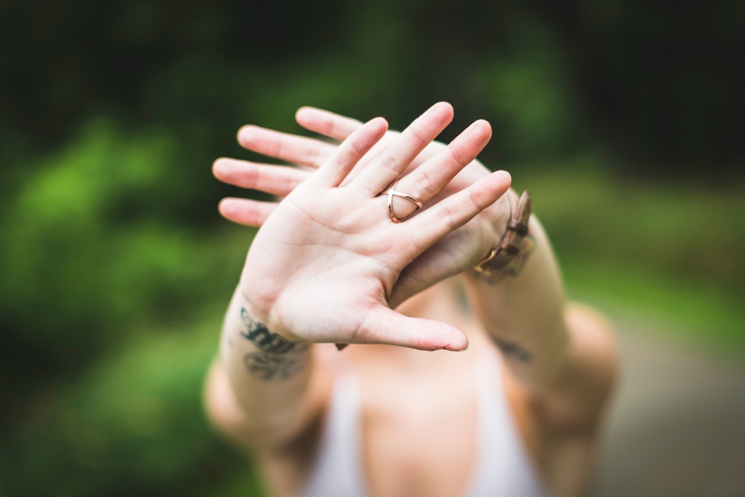 A person holding up their tattooed arms in front of their face