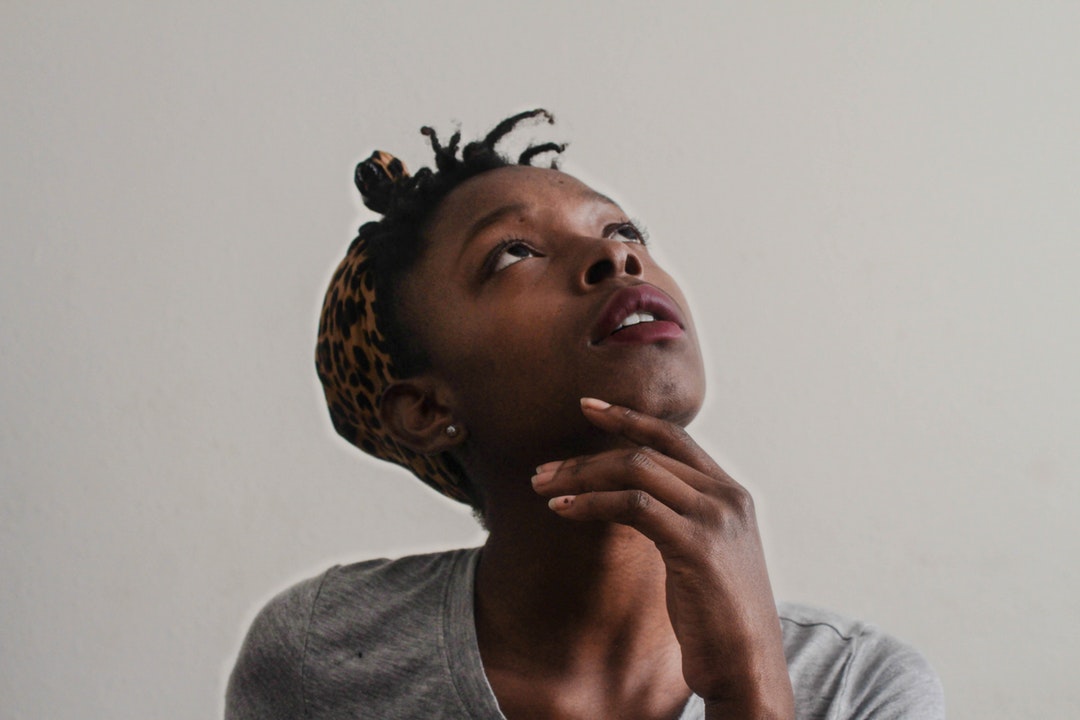 A young woman in a headscarf looking up with her hand under hair chin