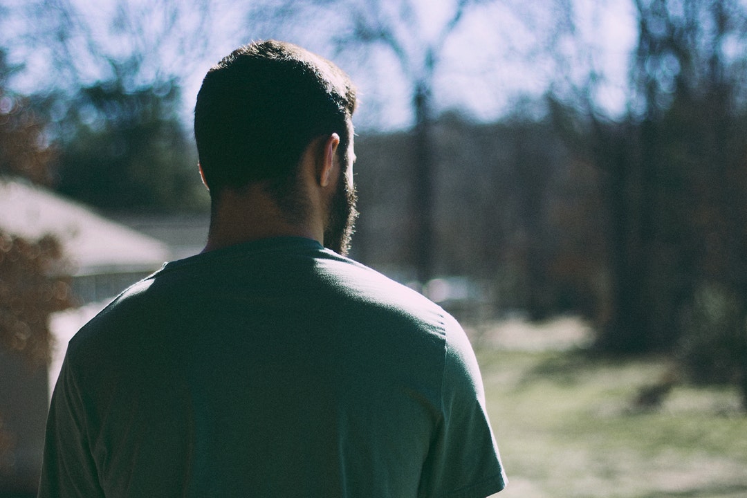 A man wearing a green shirt with his back to the camera