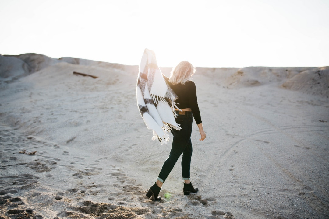 Fashionable woman walks with Aztec blanket throw white beach sand