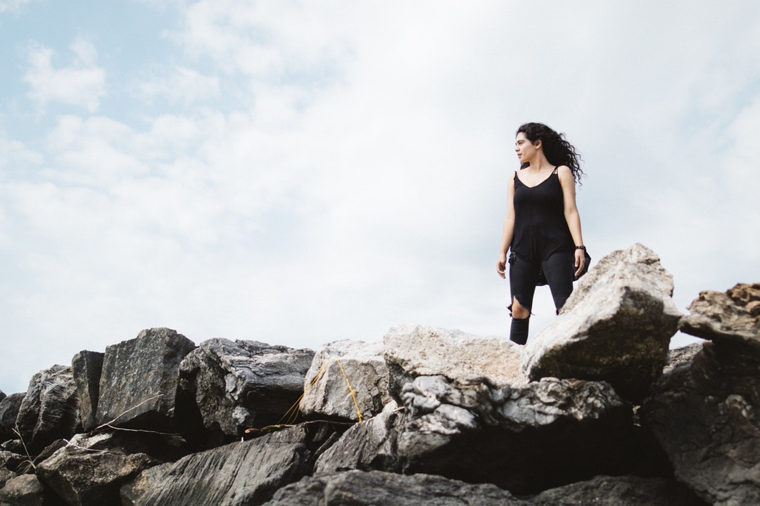 A woman wearing all black standing tall and proud on some rocks