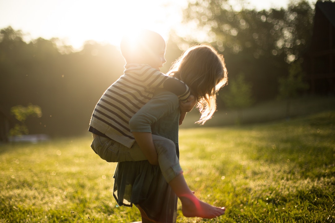 boy riding on girl's back outdoors during daytime