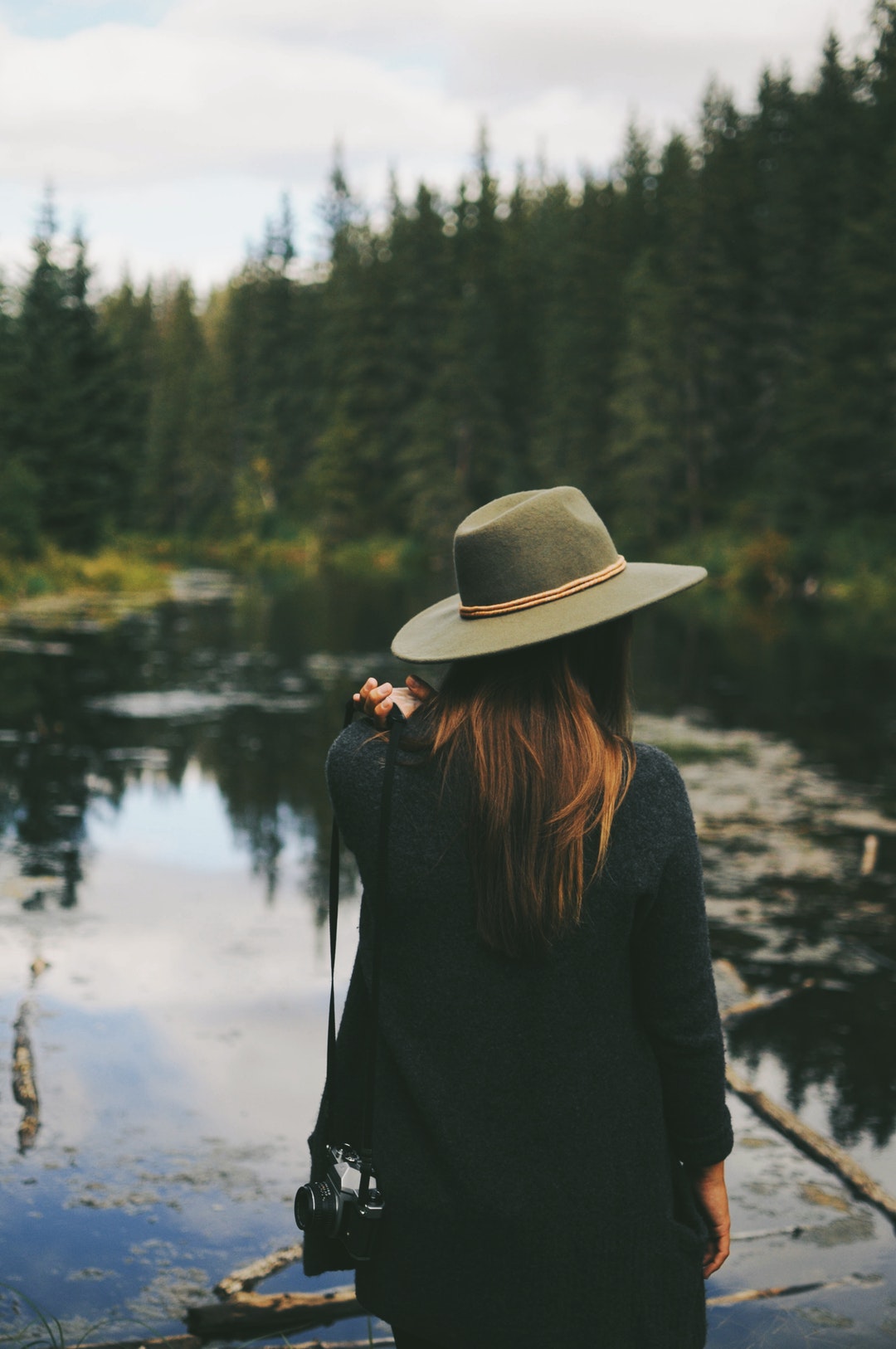 A woman wearing a hat, staring out at the lake at Mactaggart Sanctuary near Edmonton