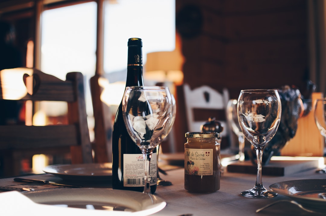 Wine bottle and glasses atop a dining table.