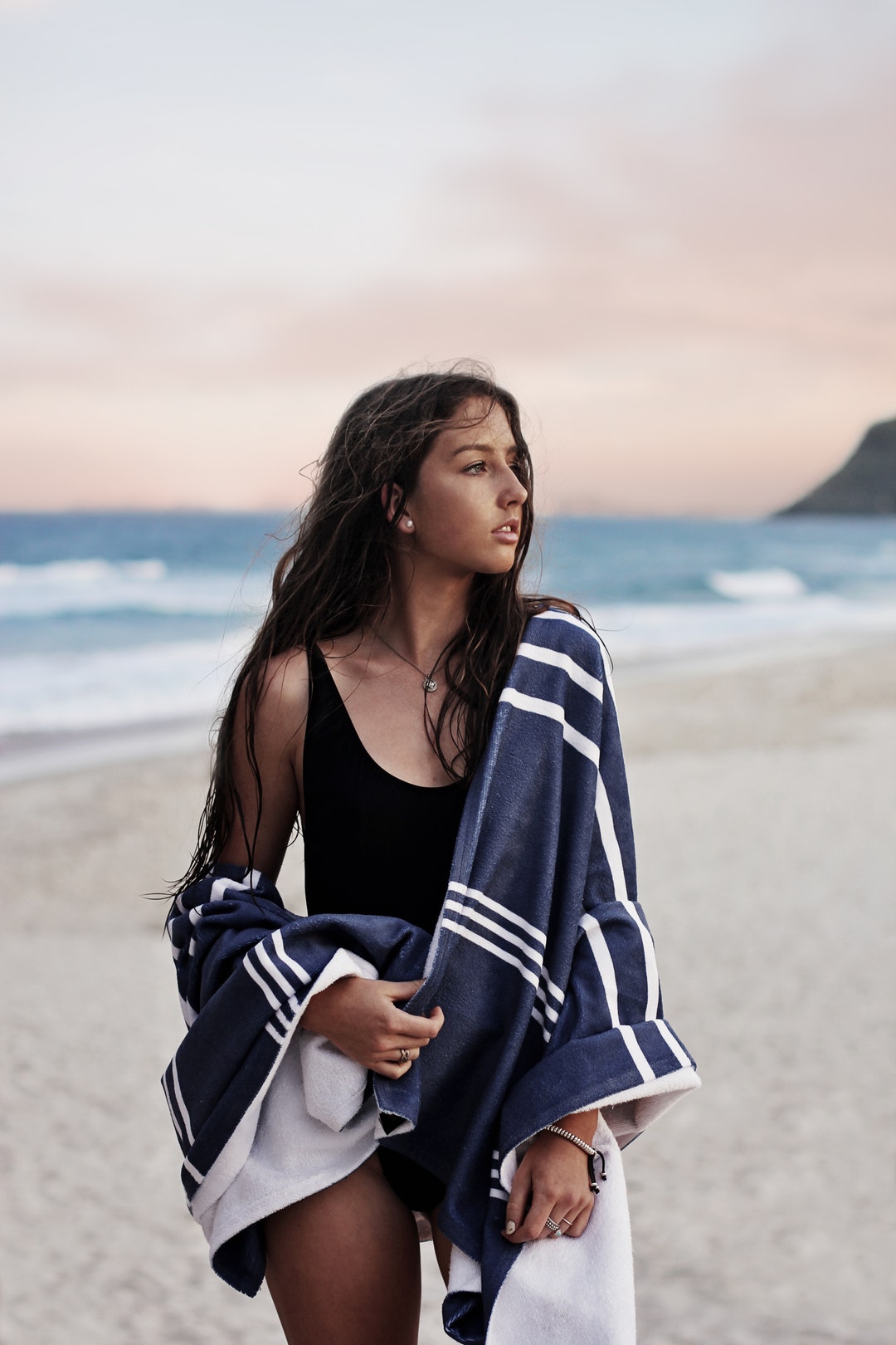 Woman in a black swimsuit covered with beach towel at the Burleigh Heads sand beach