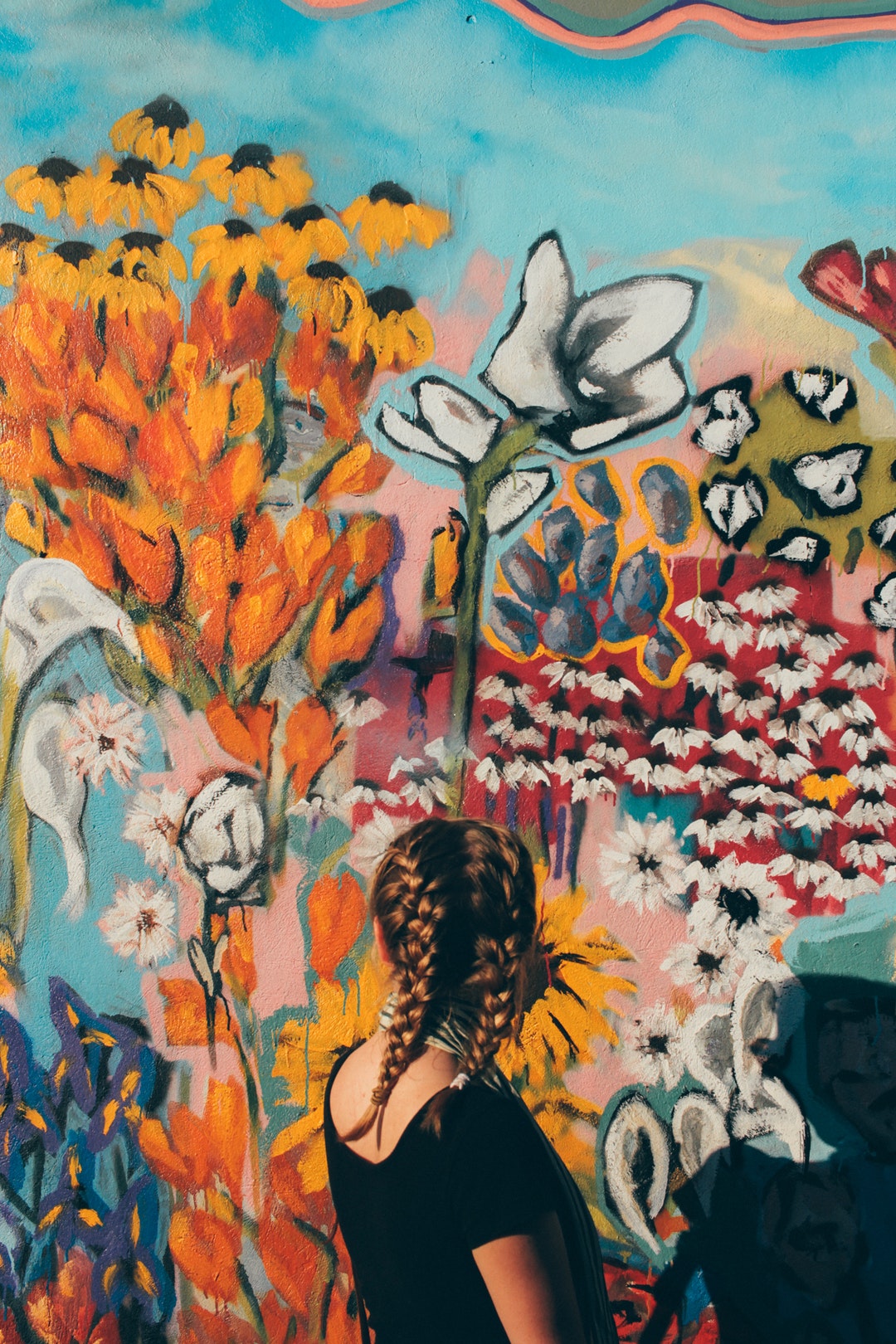 Young woman with plaited hair looking at colorful graffiti artwork in Nashville