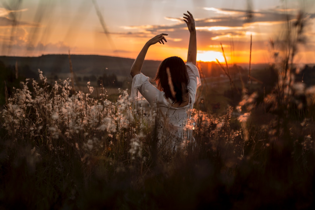 Brunette woman doing a yoga pose inside long grass in Curitiba at sunrise